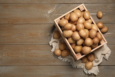 Photo of Raw fresh organic potatoes on wooden background, top view. Space for text