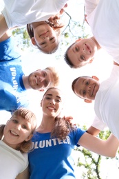 Photo of Low angle view of volunteers huddling with kids in park
