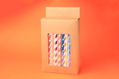 Photo of Box with many paper drinking straws on orange background