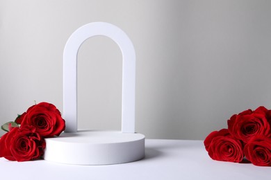 Photo of Stylish presentation for product. Beautiful red roses and geometric figures on light background, space for text