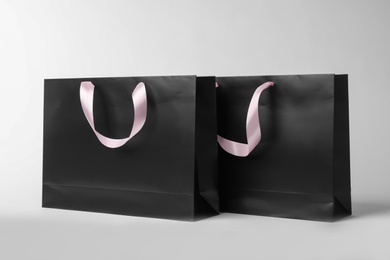 Photo of Paper shopping bags with ribbon handles on white background. Mockup for design