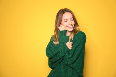 Image of Happy young woman wearing warm sweater on yellow background