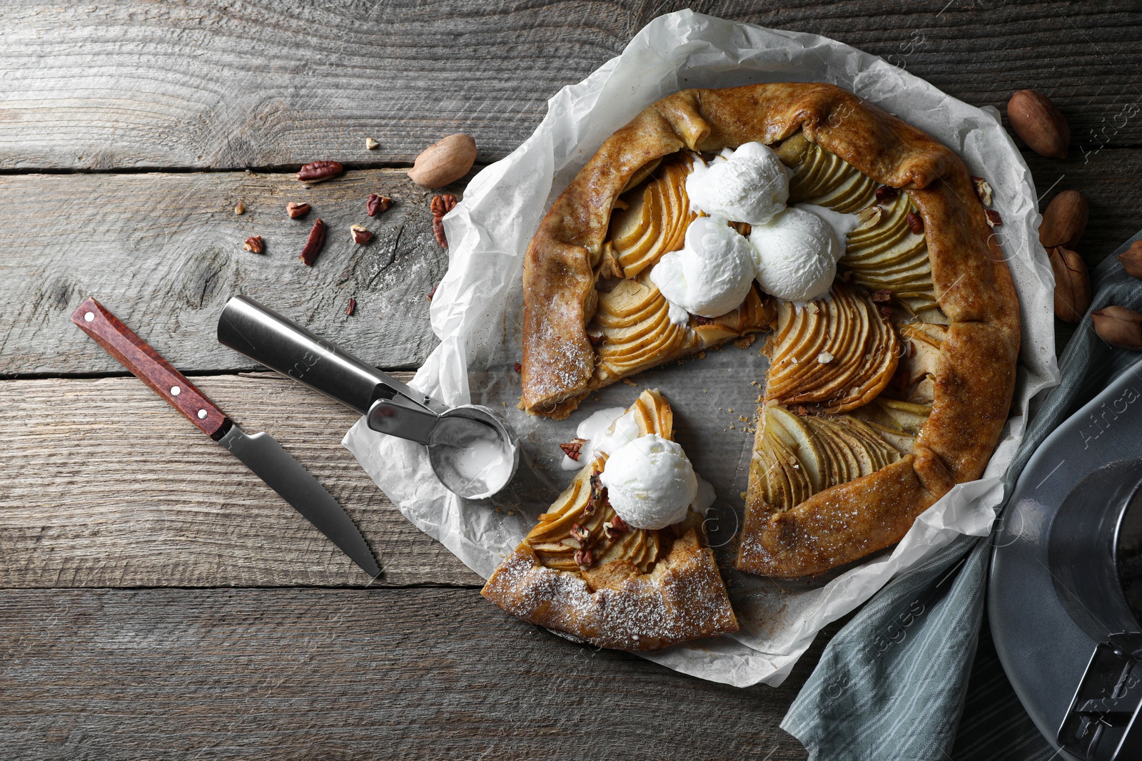 Photo of Delicious apple galette served with ice cream on wooden table, flat lay