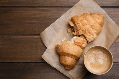 Photo of Fresh croissant and aromatic coffee on wooden table, flat lay. Space for text