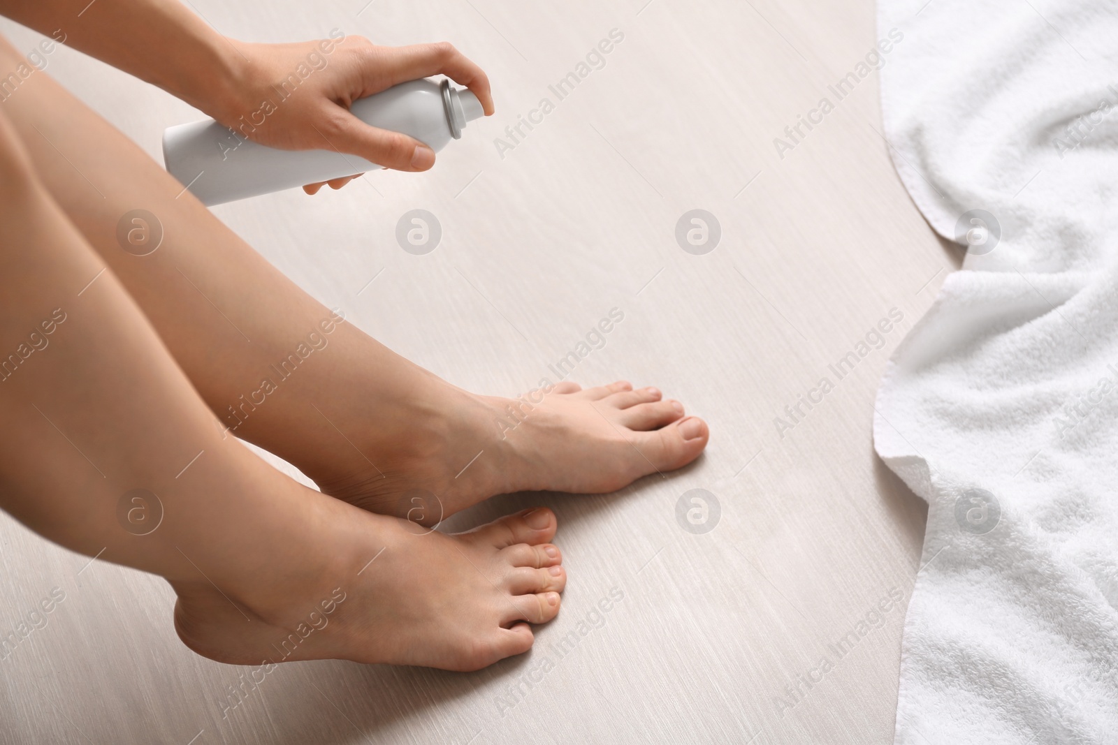 Photo of Young woman using foot deodorant at home, closeup