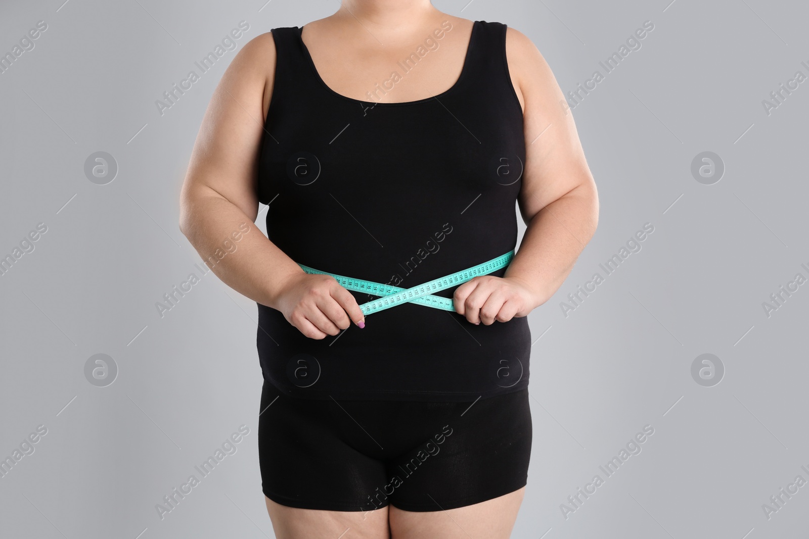 Photo of Overweight woman measuring waist before weight loss on color background