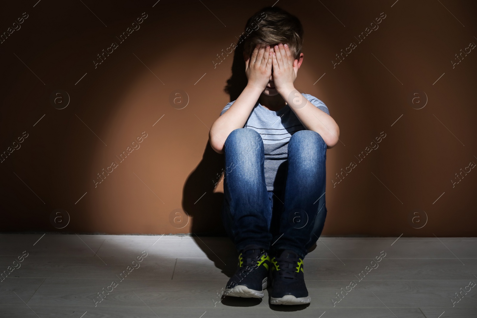 Photo of Depressed little boy sitting on floor indoors. Time to visit child psychologist