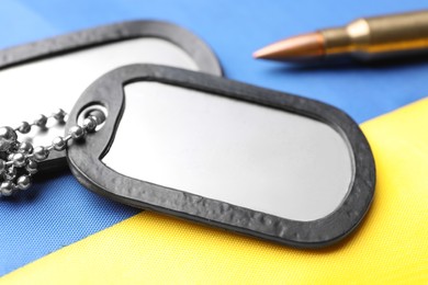 Photo of Military ID tags and bullet on national flag of Ukraine, closeup