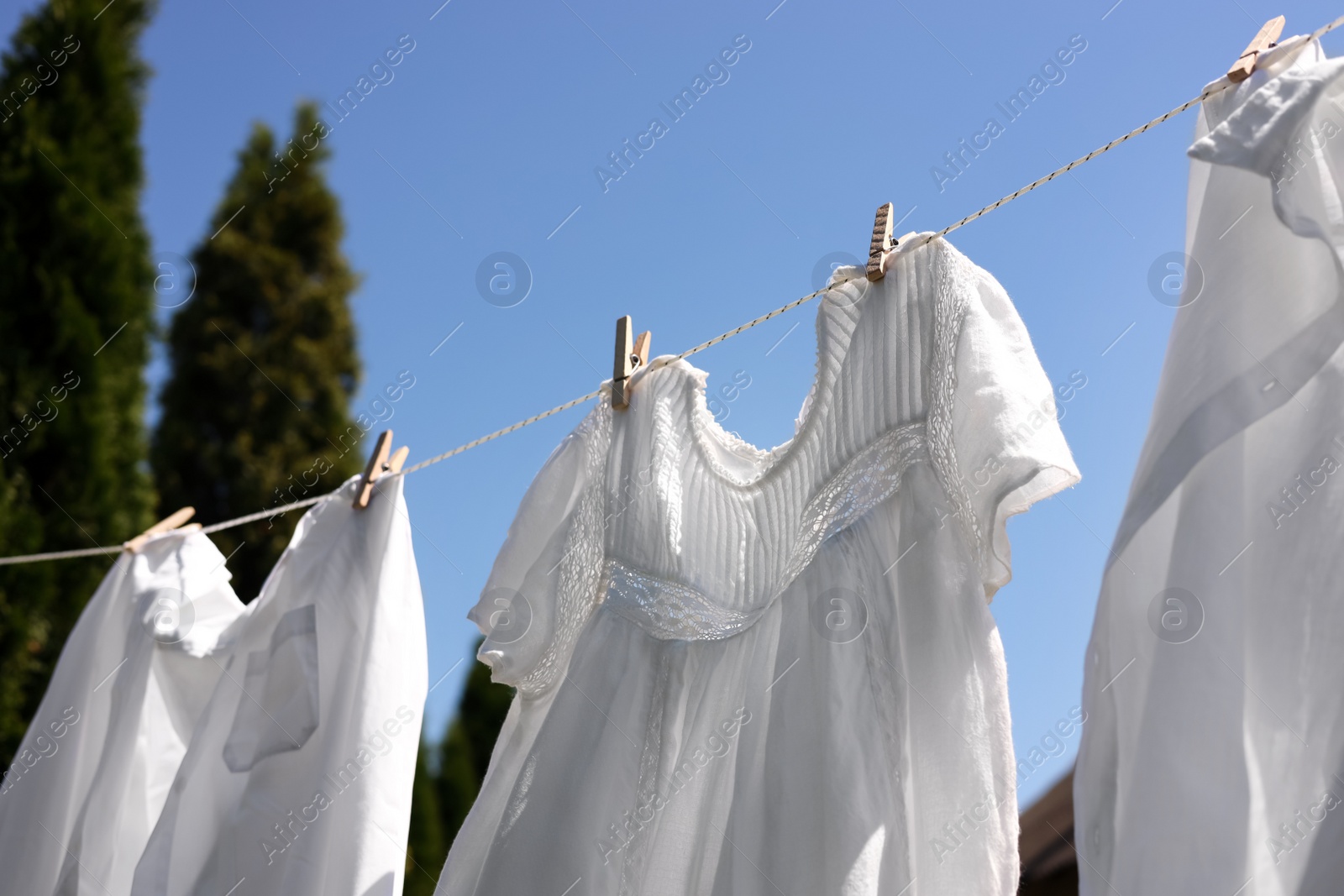 Photo of Clean clothes hanging on washing line in garden. Drying laundry