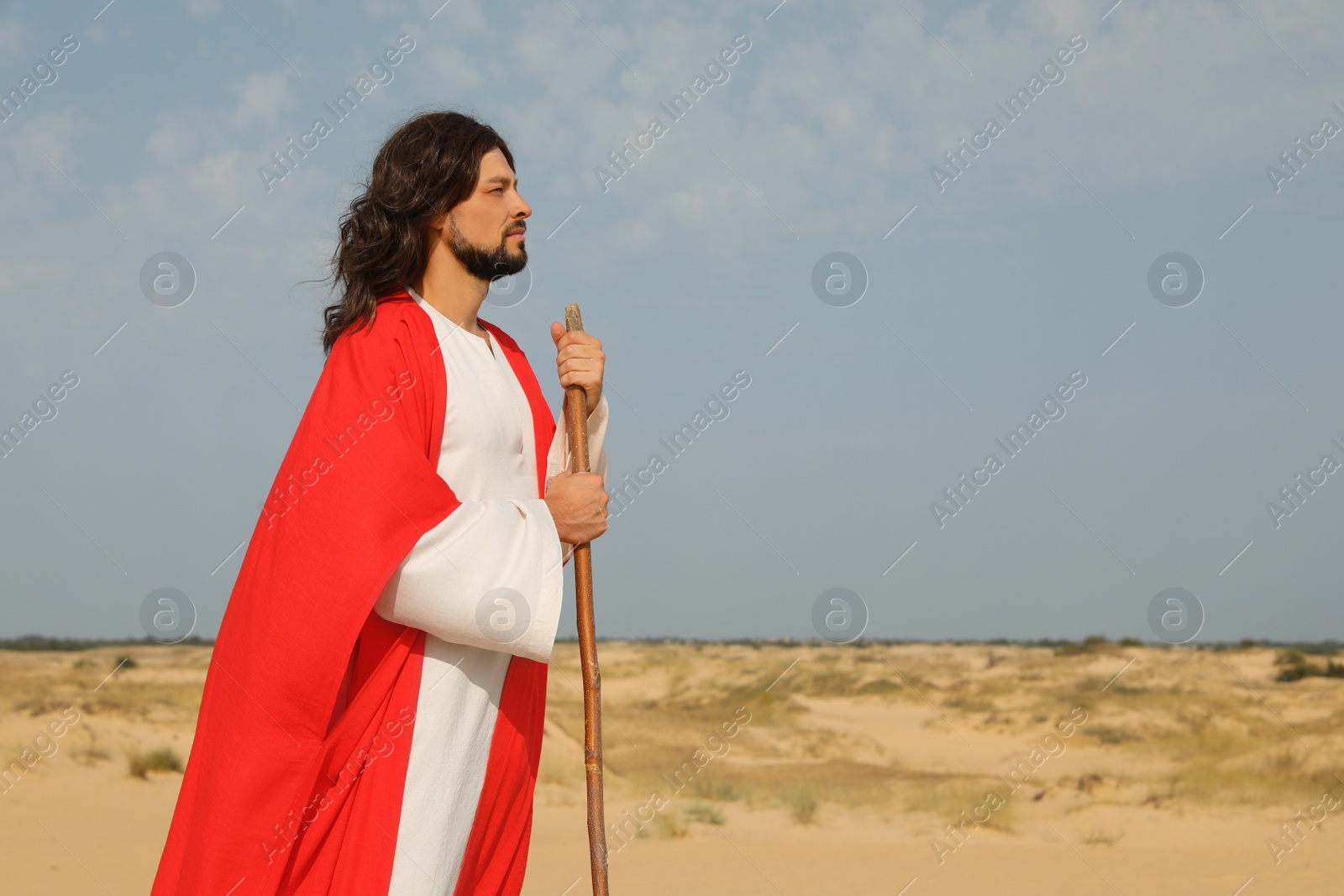 Photo of Jesus Christ walking with stick in desert. Space for text