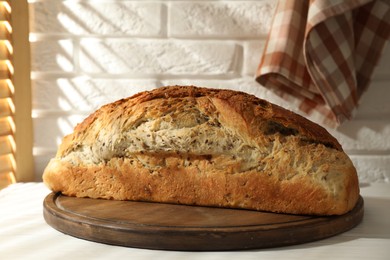 Photo of Freshly baked sourdough bread on white wooden table indoors