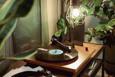 Photo of Stylish turntable with vinyl record on table indoors