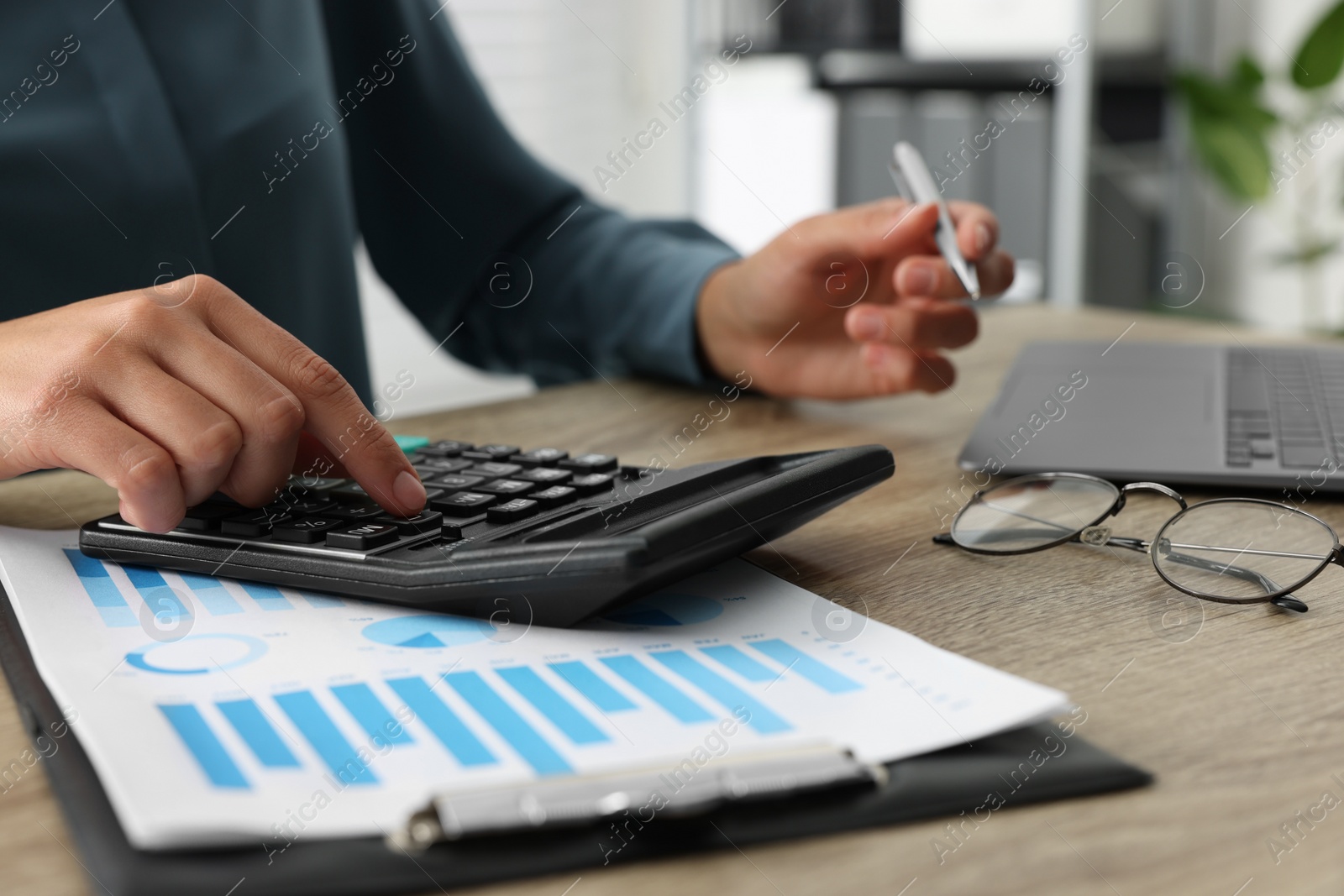 Photo of Woman using calculator at wooden table, closeup