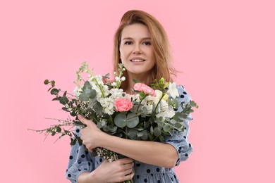 Beautiful woman with bouquet of flowers on pink background