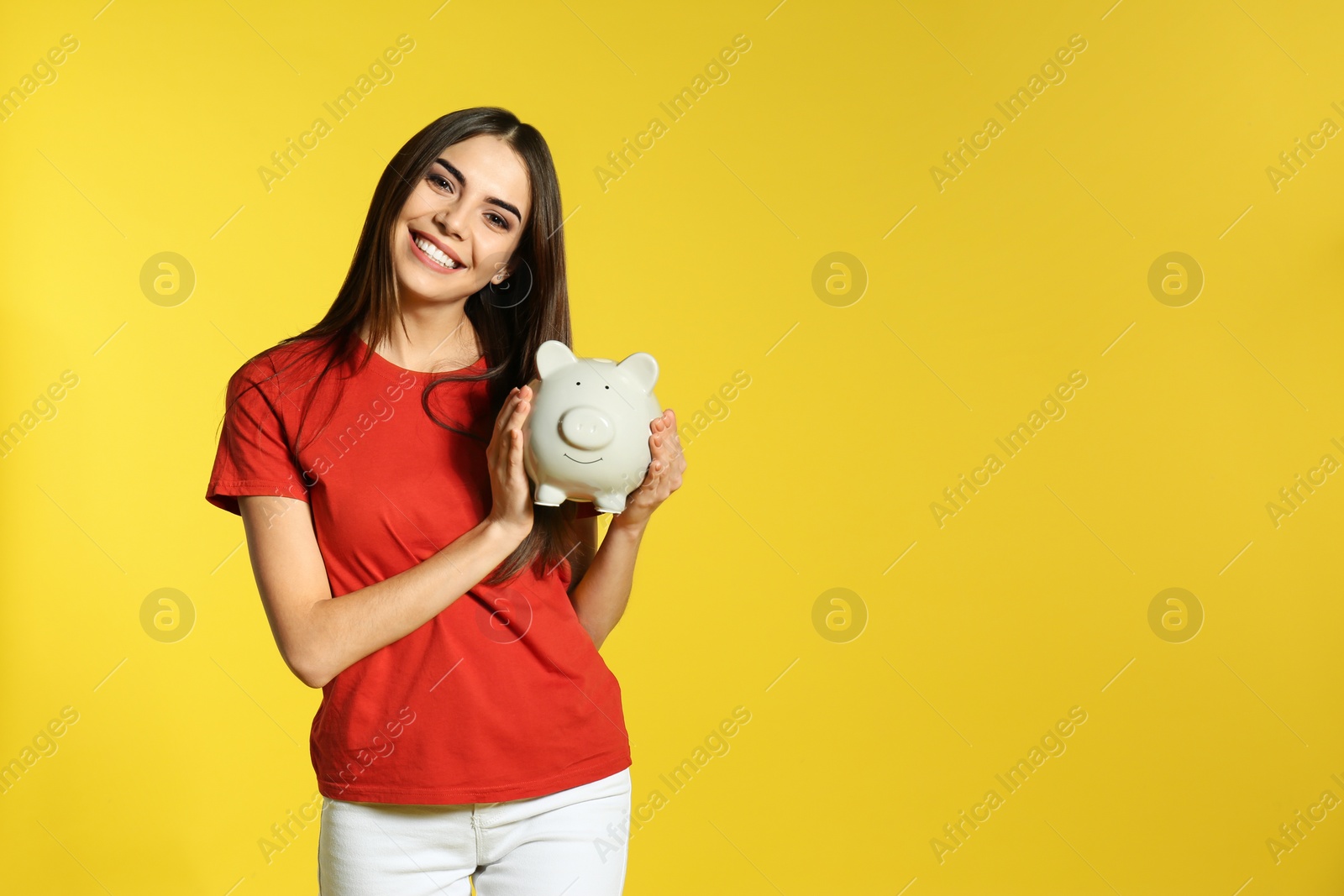 Photo of Young woman with piggy bank on color background, space for text. Money saving
