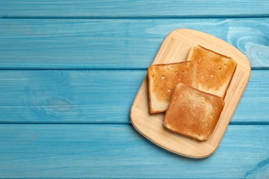 Photo of Slicestasty toasted bread on turquoise wooden table, top view. Space for text
