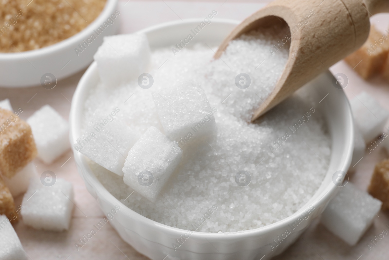 Photo of Bowl with refined and granulated white sugar on table, closeup