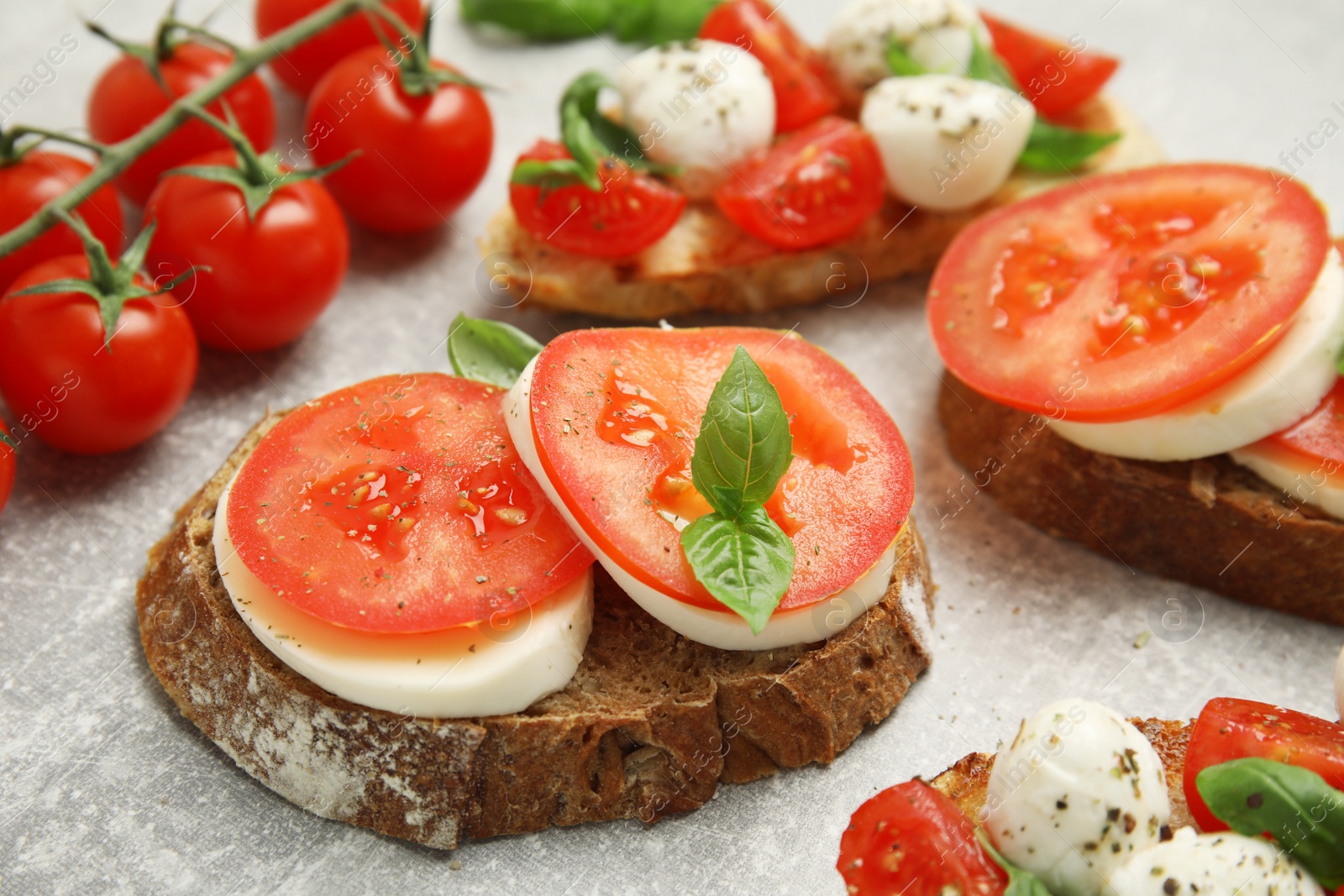 Photo of Delicious sandwiches with mozzarella, fresh tomatoes and basil on light grey table