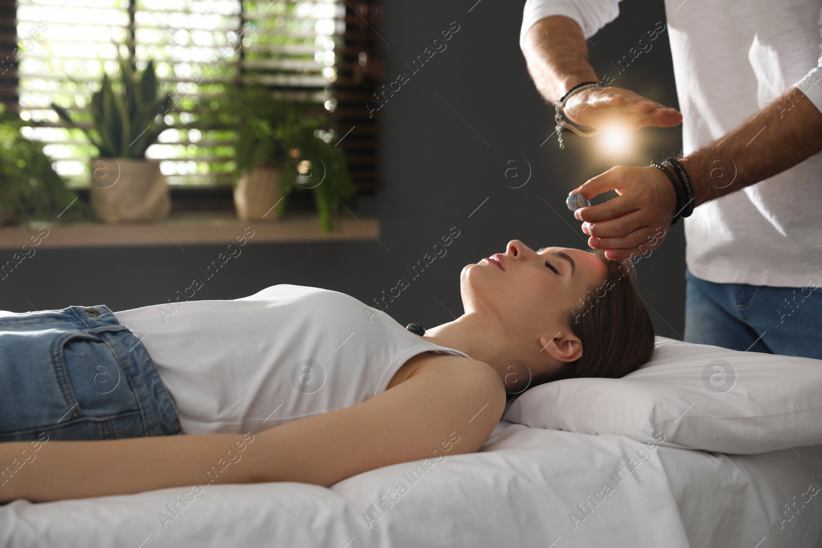 Photo of Young woman during crystal healing session in therapy room