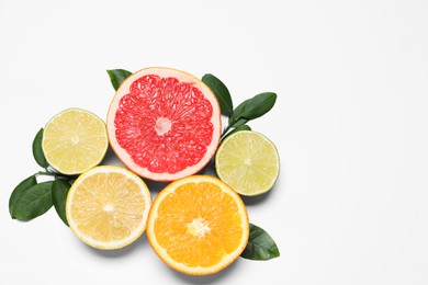 Photo of Different cut citrus fruits and leaves on white table, flat lay. Space for text