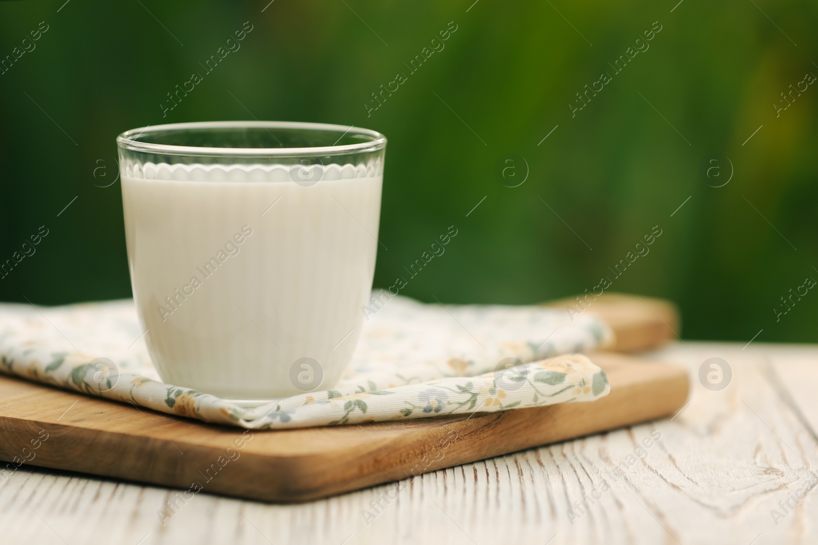 Photo of Glass of tasty fresh milk on white wooden table, closeup. Space for text
