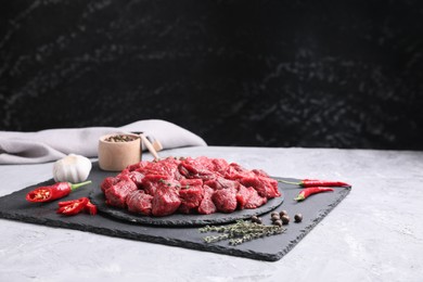 Photo of Pieces of raw beef meat, products and spices on grey textured table. Space for text