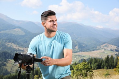 Professional photographer with modern camera in mountains