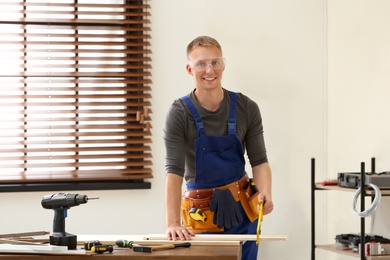 Photo of Handsome young working man using hand saw indoors. Home repair