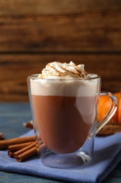 Photo of Delicious pumpkin latte on blue wooden table, closeup