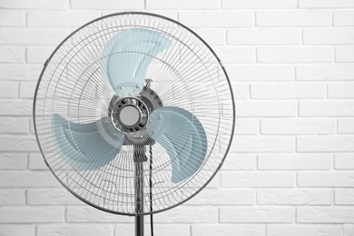 Electric fan near white brick wall. Summer heat