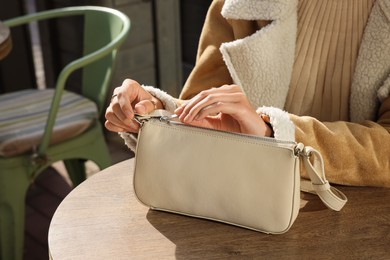 Fashionable woman with stylish bag at table in outdoor cafe, closeup