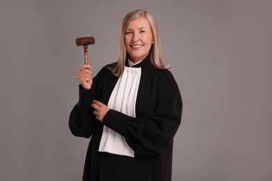 Photo of Smiling senior judge with gavel on grey background