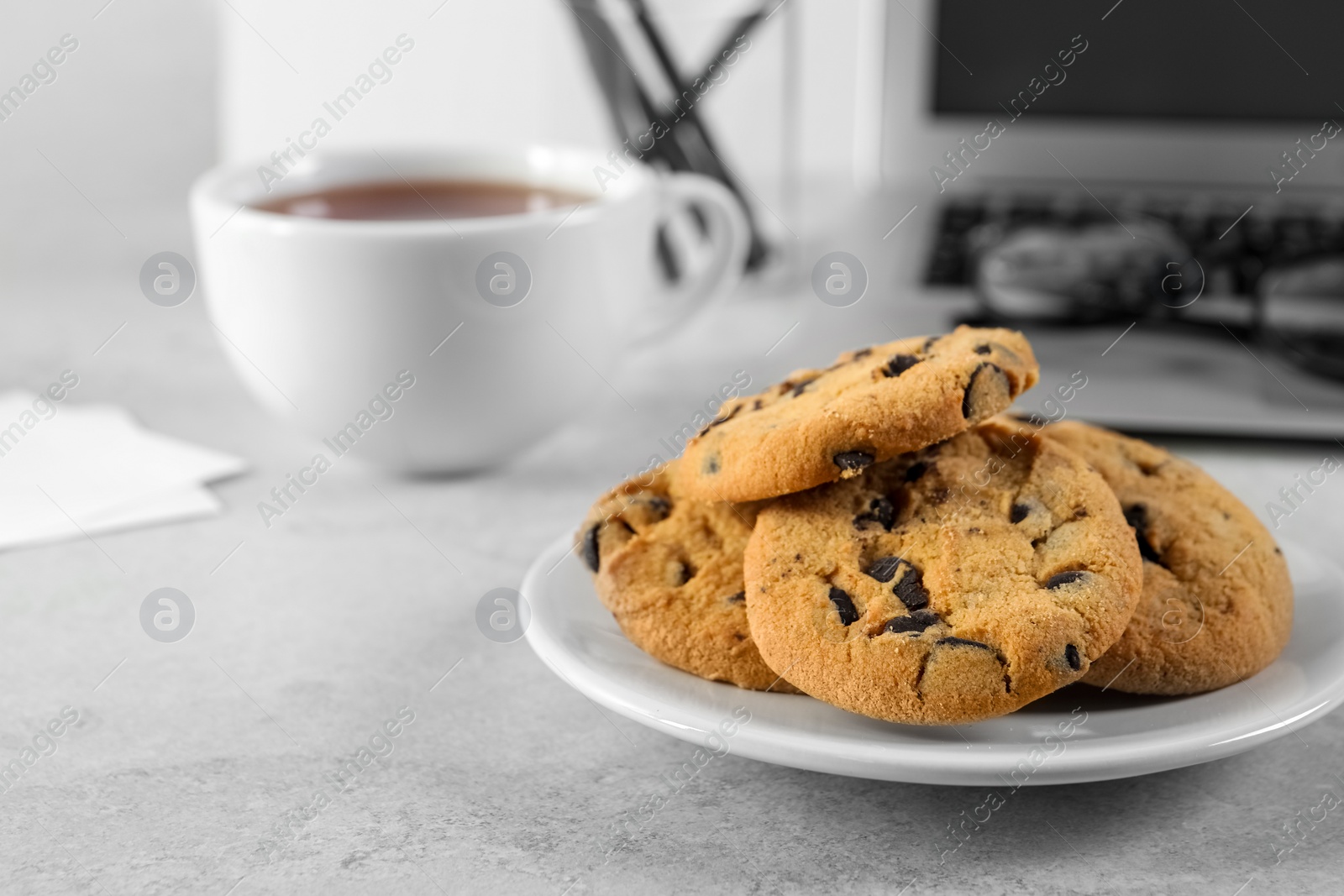 Photo of Chocolate chip cookies on light gray table at workplace, space for text