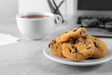 Photo of Chocolate chip cookies on light gray table at workplace, space for text