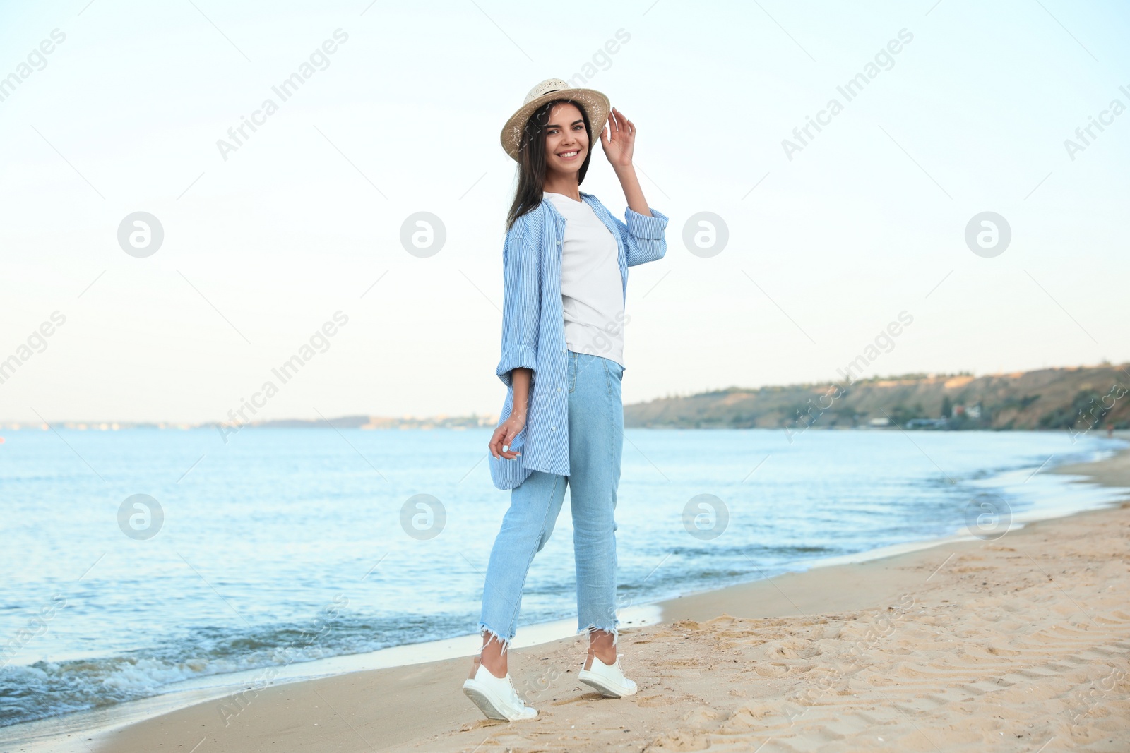 Photo of Beautiful young woman in casual outfit on beach