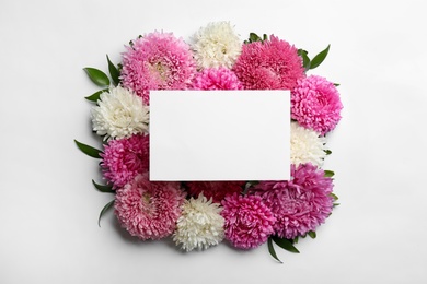 Composition with blank card and beautiful asters on white background, top view. Autumn flowers