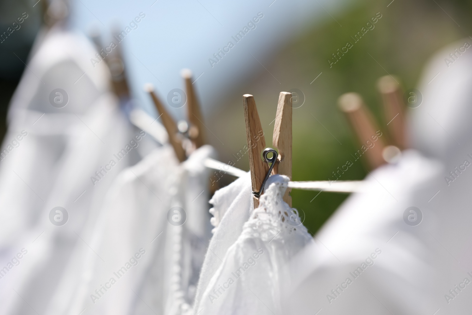 Photo of Clean clothes drying outdoors, closeup. Focus on clothespin