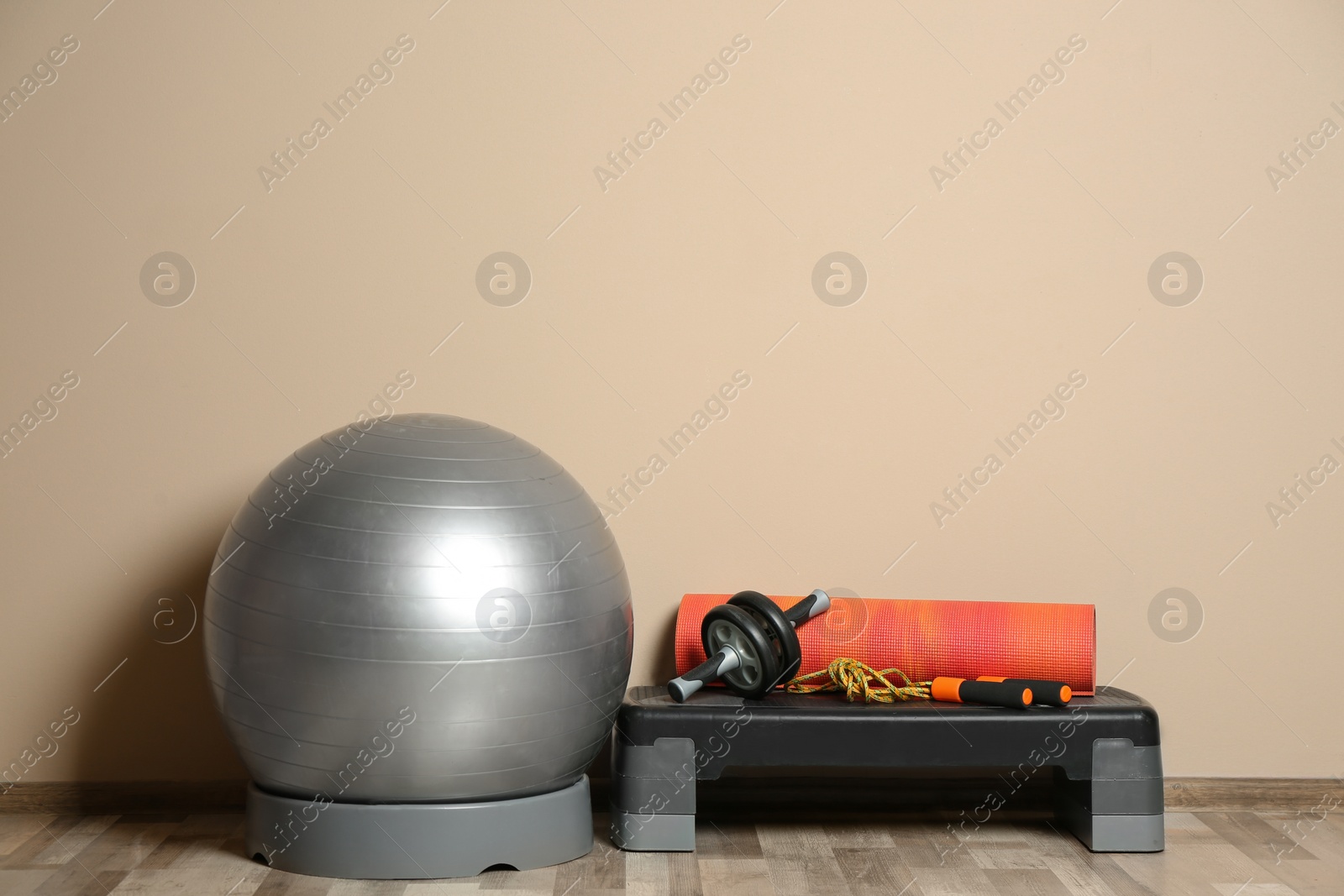 Photo of Set of fitness inventory on floor near color wall. Space for text