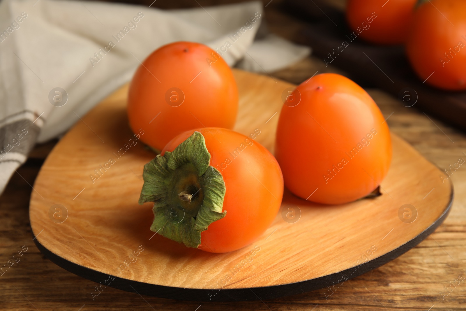 Photo of Tasty ripe persimmons on wooden table, closeup