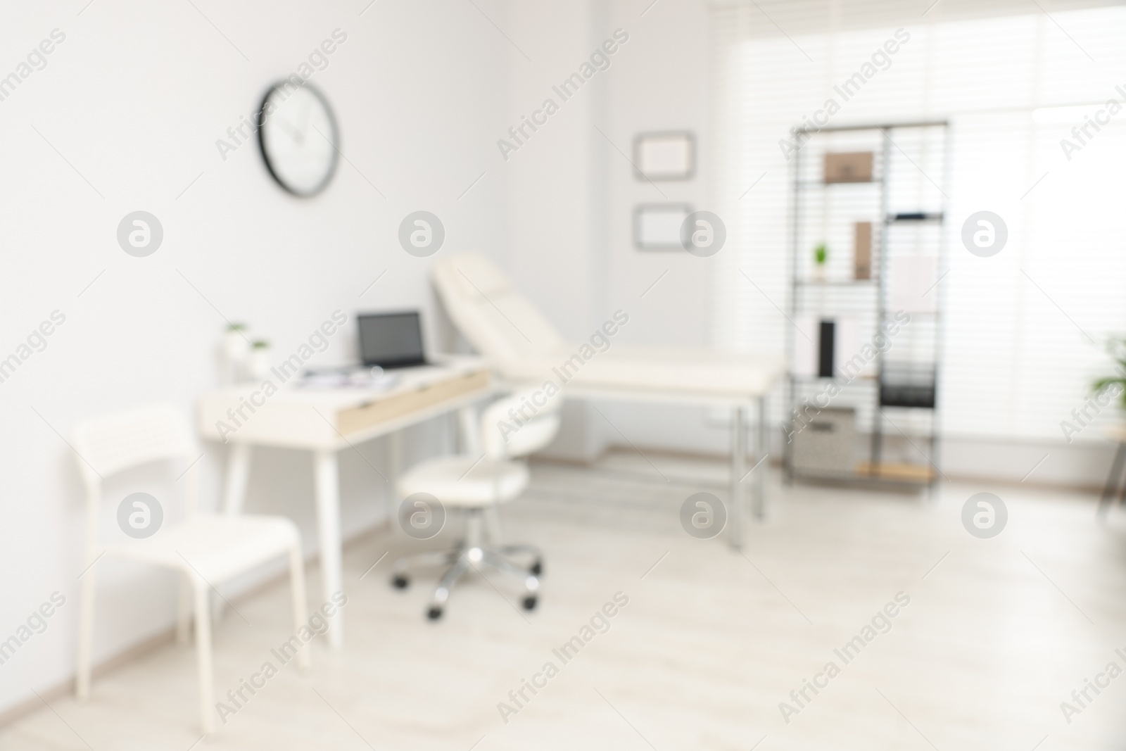 Photo of Blurred view of modern medical office with doctor's workplace and examination table in clinic