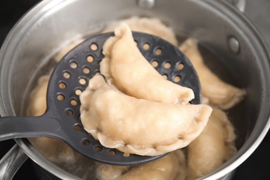Photo of Dumplings (varenyky) with cottage cheese on skimmer over pot, closeup