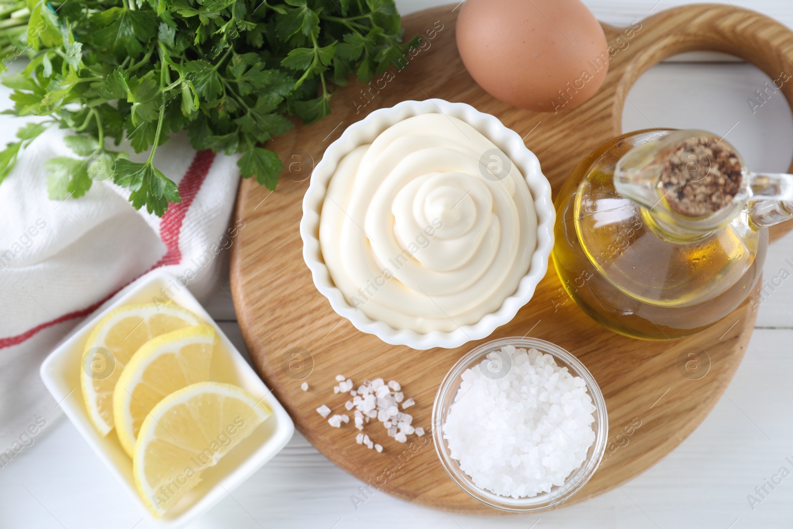 Photo of Fresh mayonnaise sauce in bowl and ingredients on white wooden table, flat lay