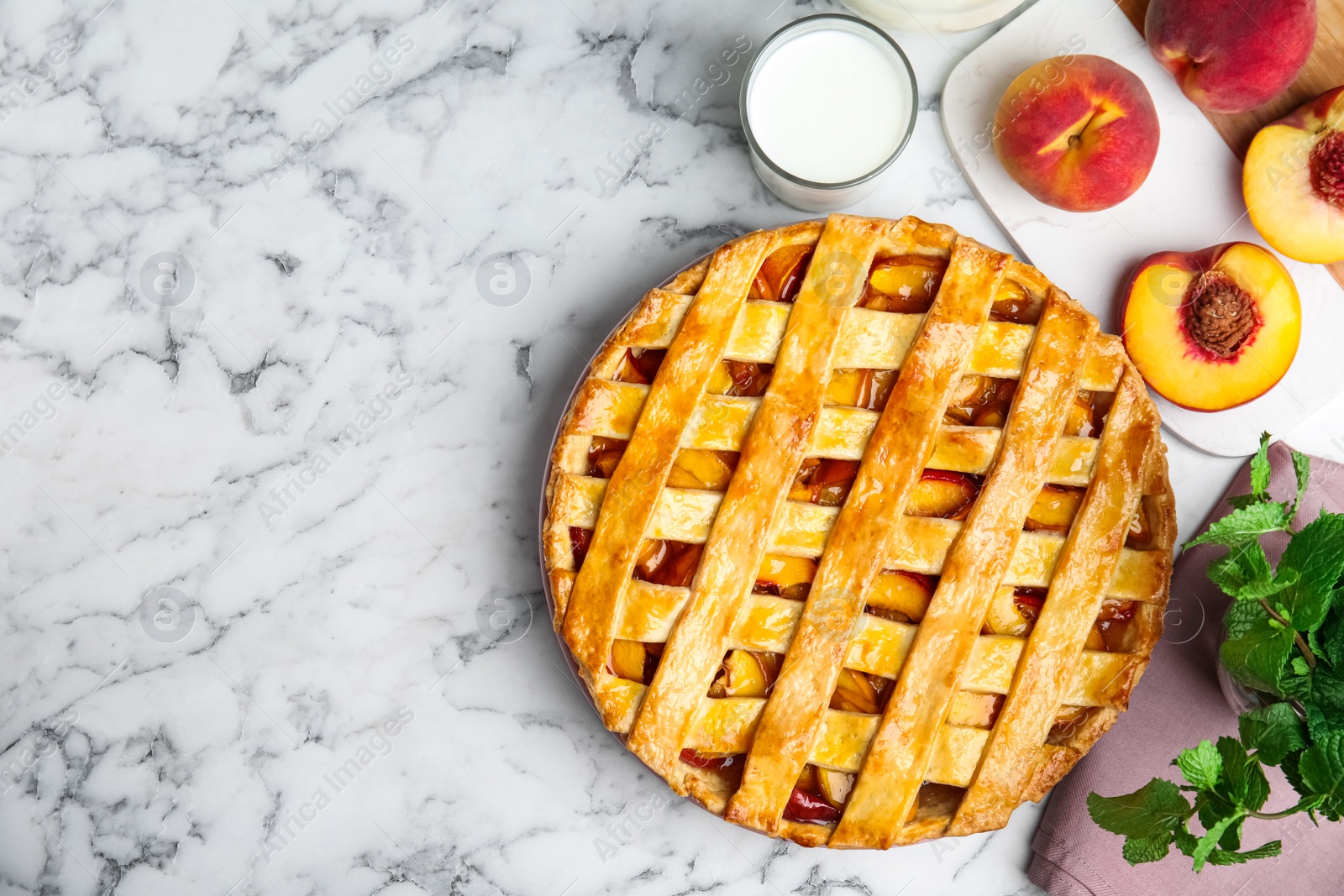 Photo of Delicious peach pie and fresh fruits on white marble table, flat lay. Space for text