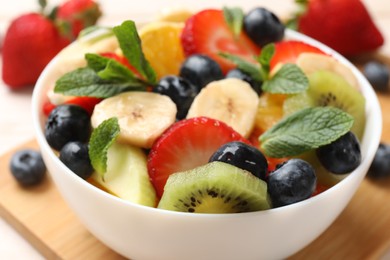 Tasty fruit salad in bowl on table, closeup