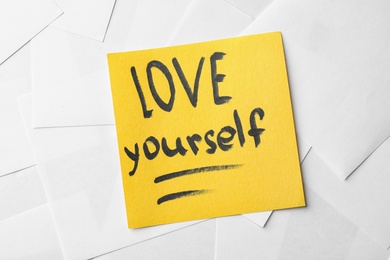 Photo of Note with words LOVE YOURSELF on paper sheets, top view