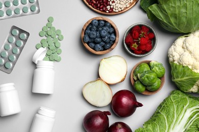 Many prebiotic pills and food on grey background, flat lay