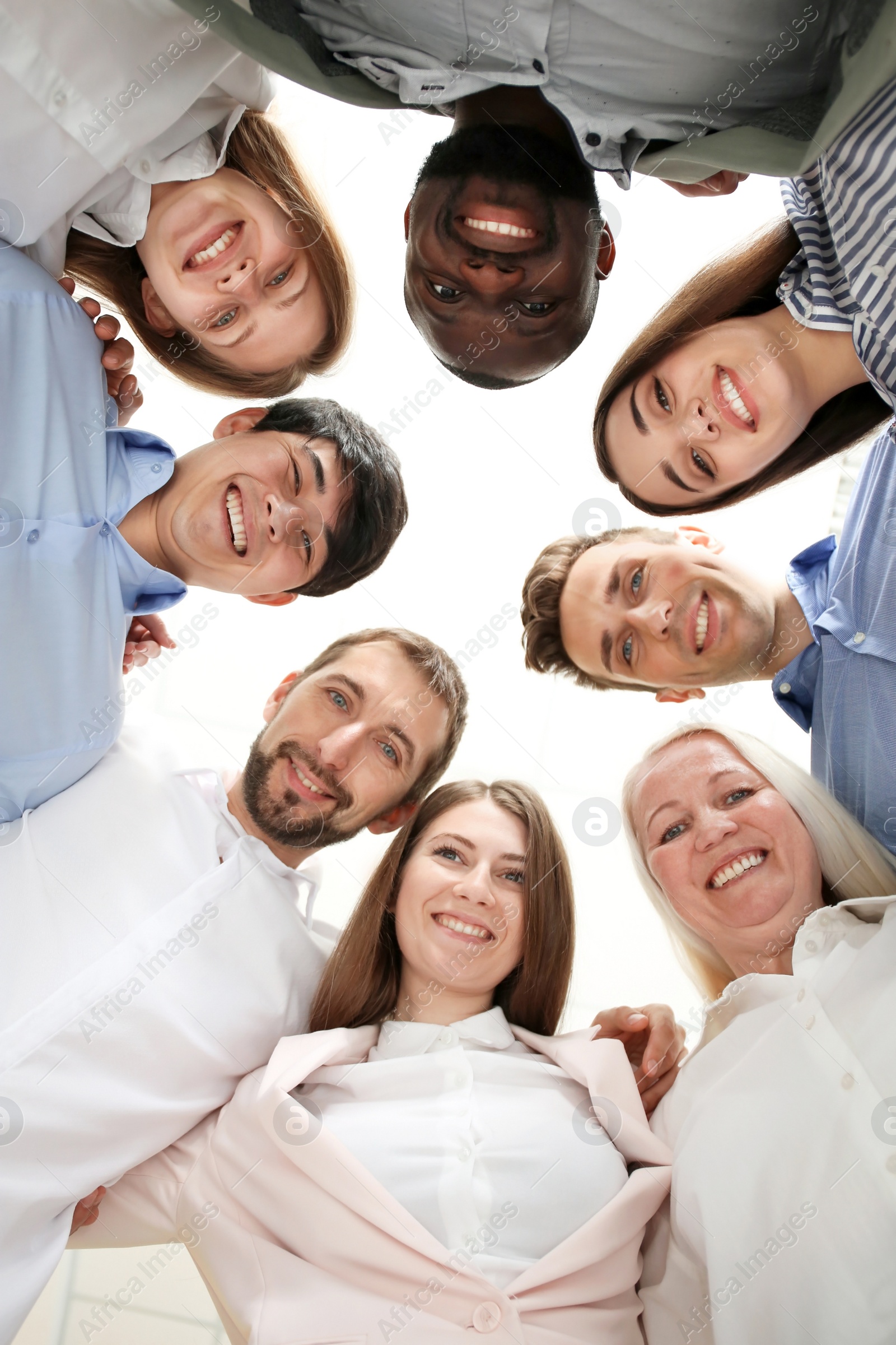 Photo of People standing together against light background, bottom view. Unity concept