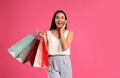 Photo of Beautiful young woman with paper shopping bags on pink background