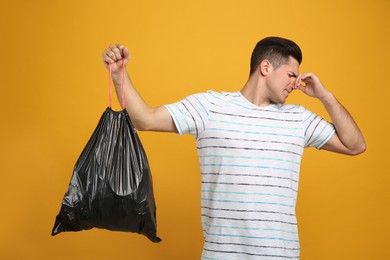 Man holding full garbage bag on yellow background