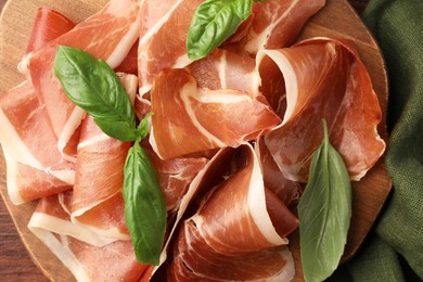 Photo of Slices of tasty cured ham and basil on table, top view